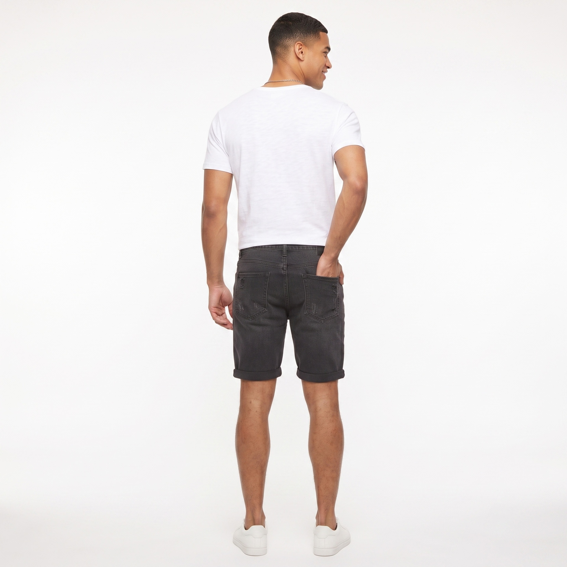 Homem de costas com t-shirt branca, calções pretos e tênis brancos