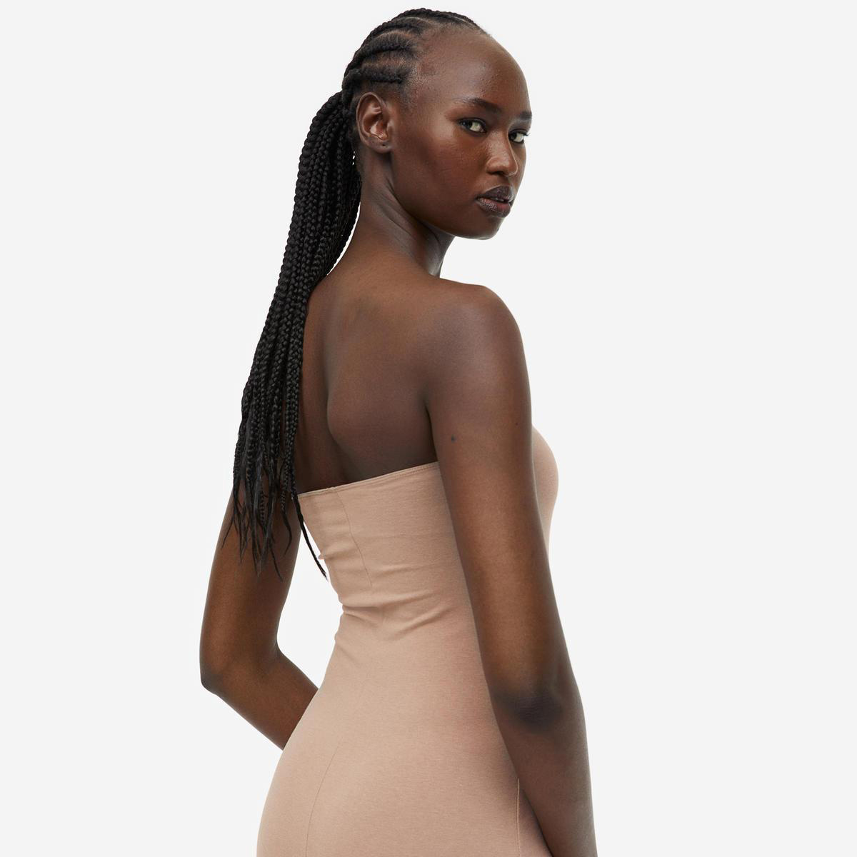Mulher de pele escura com vestido bege justo sem alças