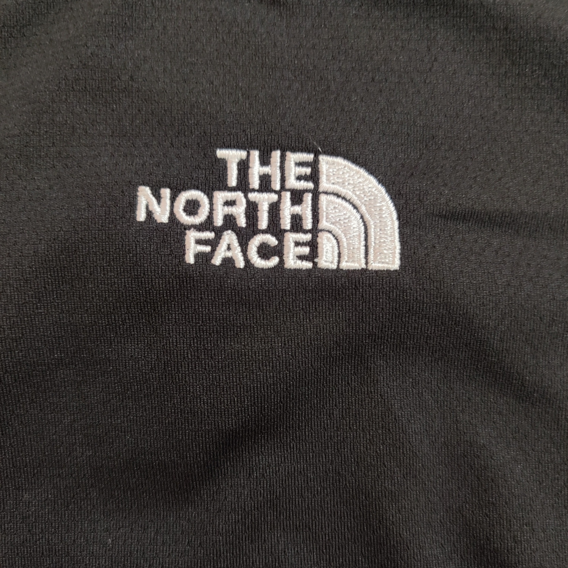 Bordado branco THE NORTH FACE em pano preto.