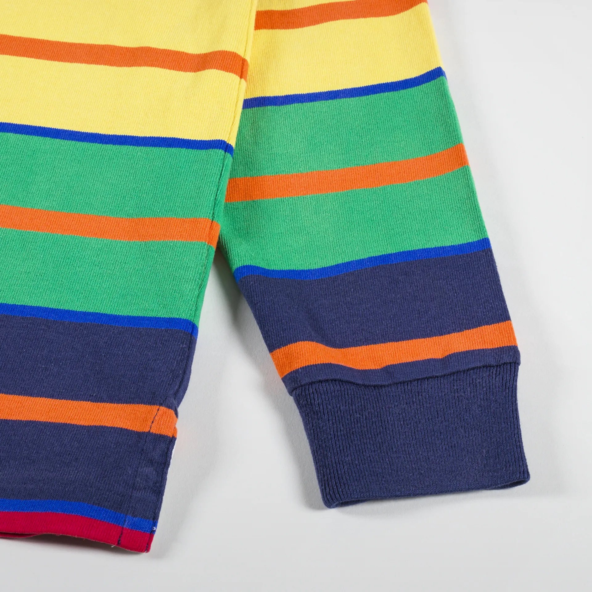 Peça de roupa com riscas coloridas em malha e punho canelado azul escuro