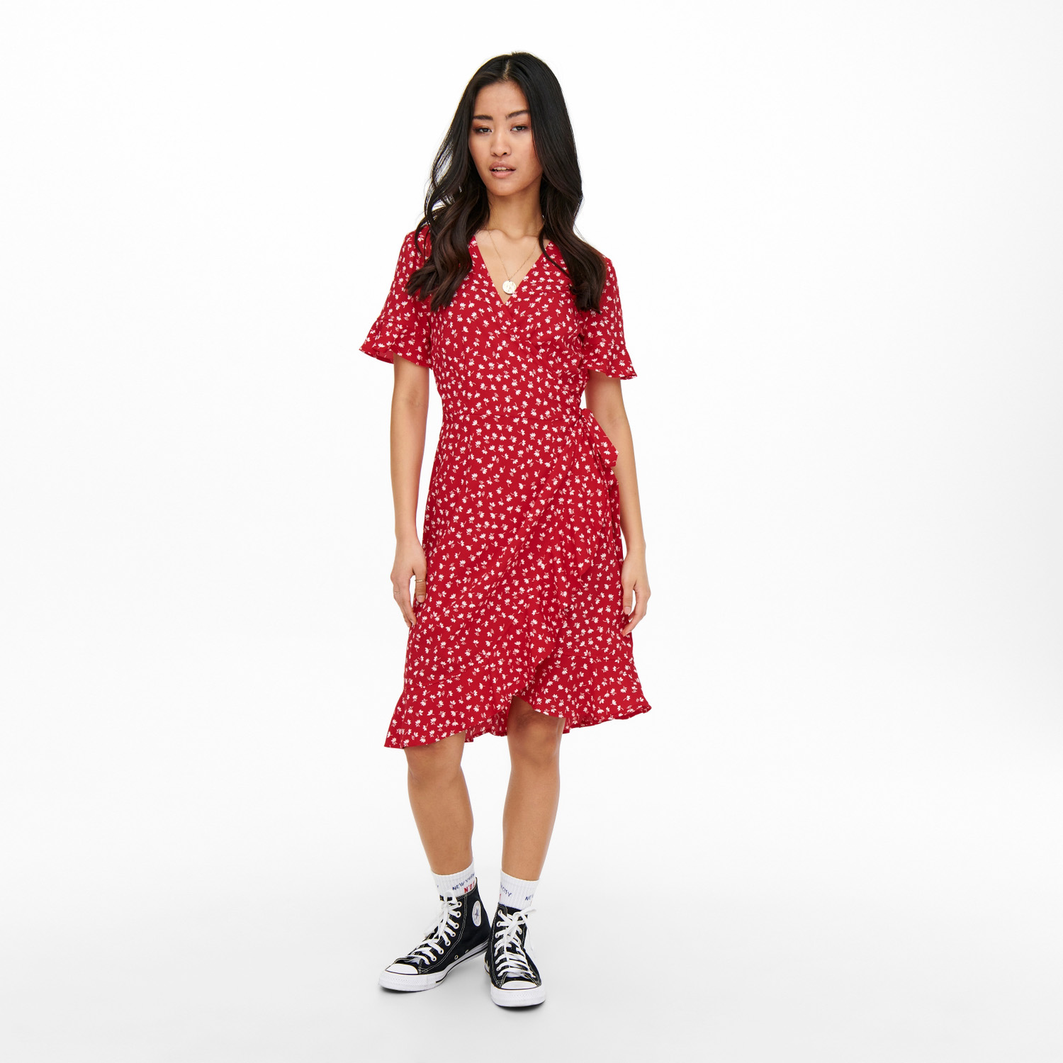 Vestido vermelho de corações brancos com botões, comprimento até joelhos, usado com sapatilhas pretas e meias brancas