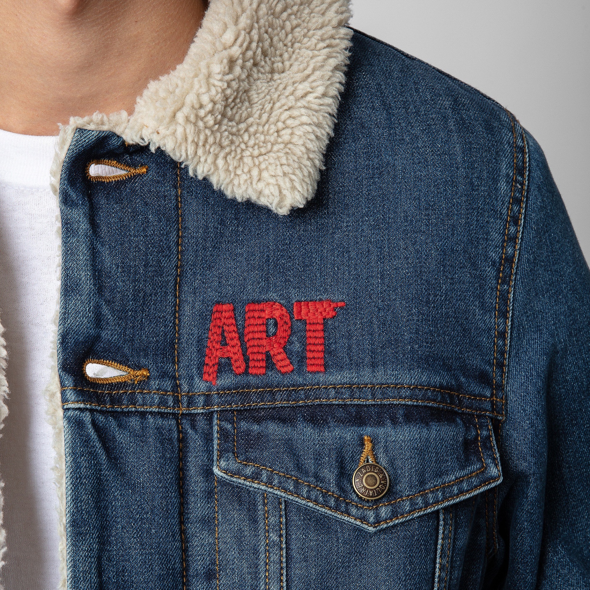 Casaco de ganga azul com gola de pelo bege e bordado vermelho ART no peito