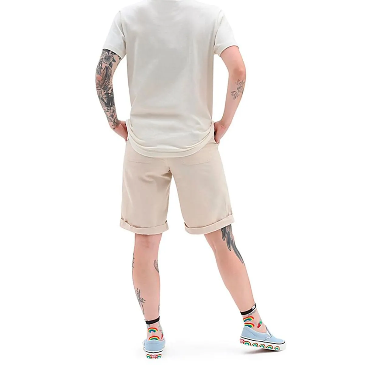 Homem com t-shirt bege, calções bege, meias e sapatos com padrão arco-íris