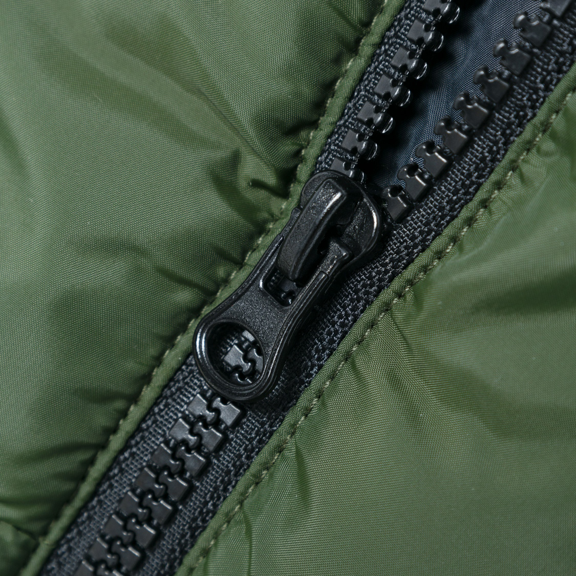 Fecho de correr preto em tecido verde acolchoado