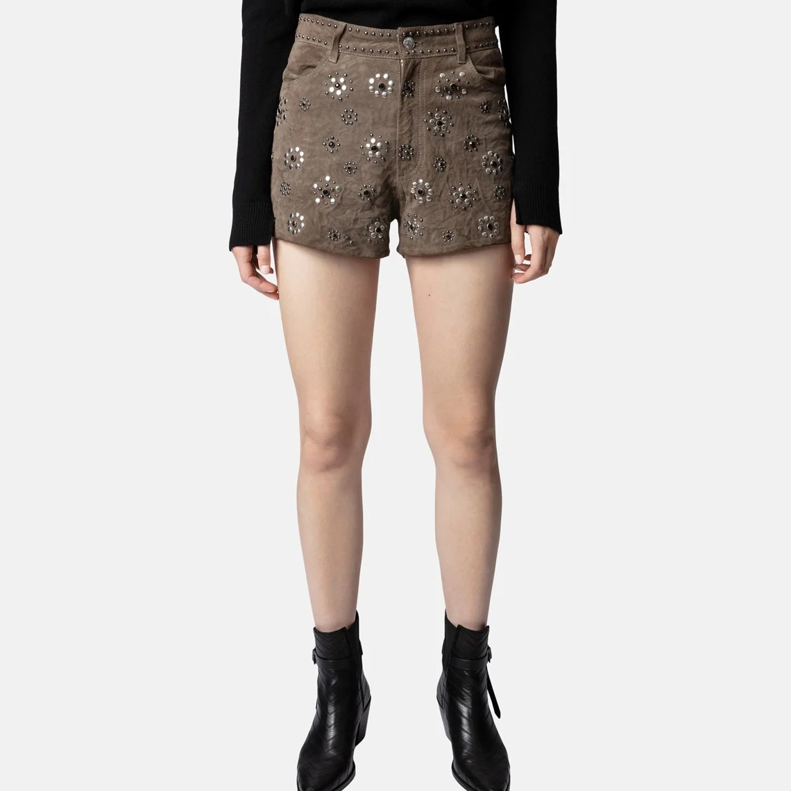 Shorts castanhos com rebites metálicos em forma de flores e botins pretos