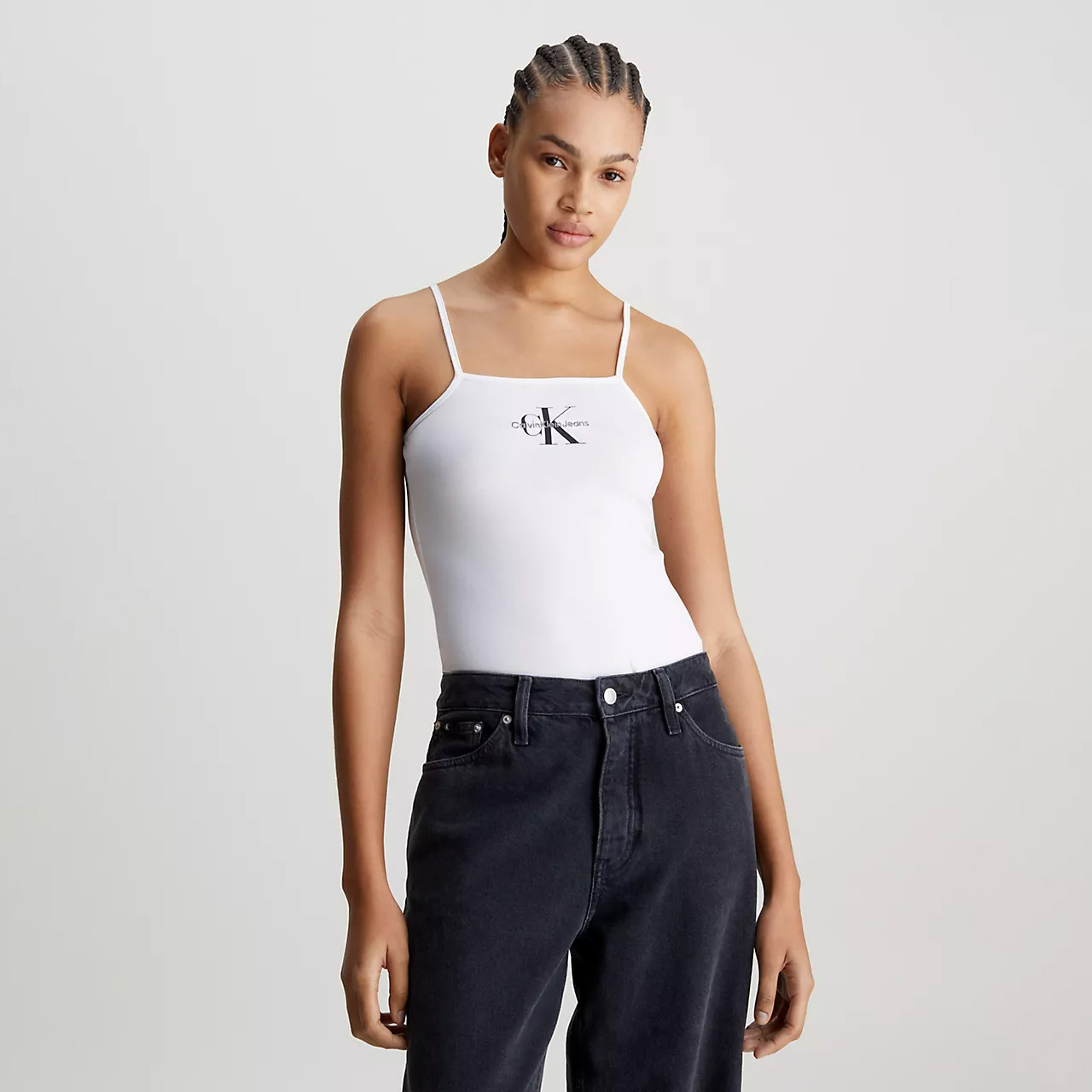 Mulher com top branco Calvin Klein Jeans e jeans pretos