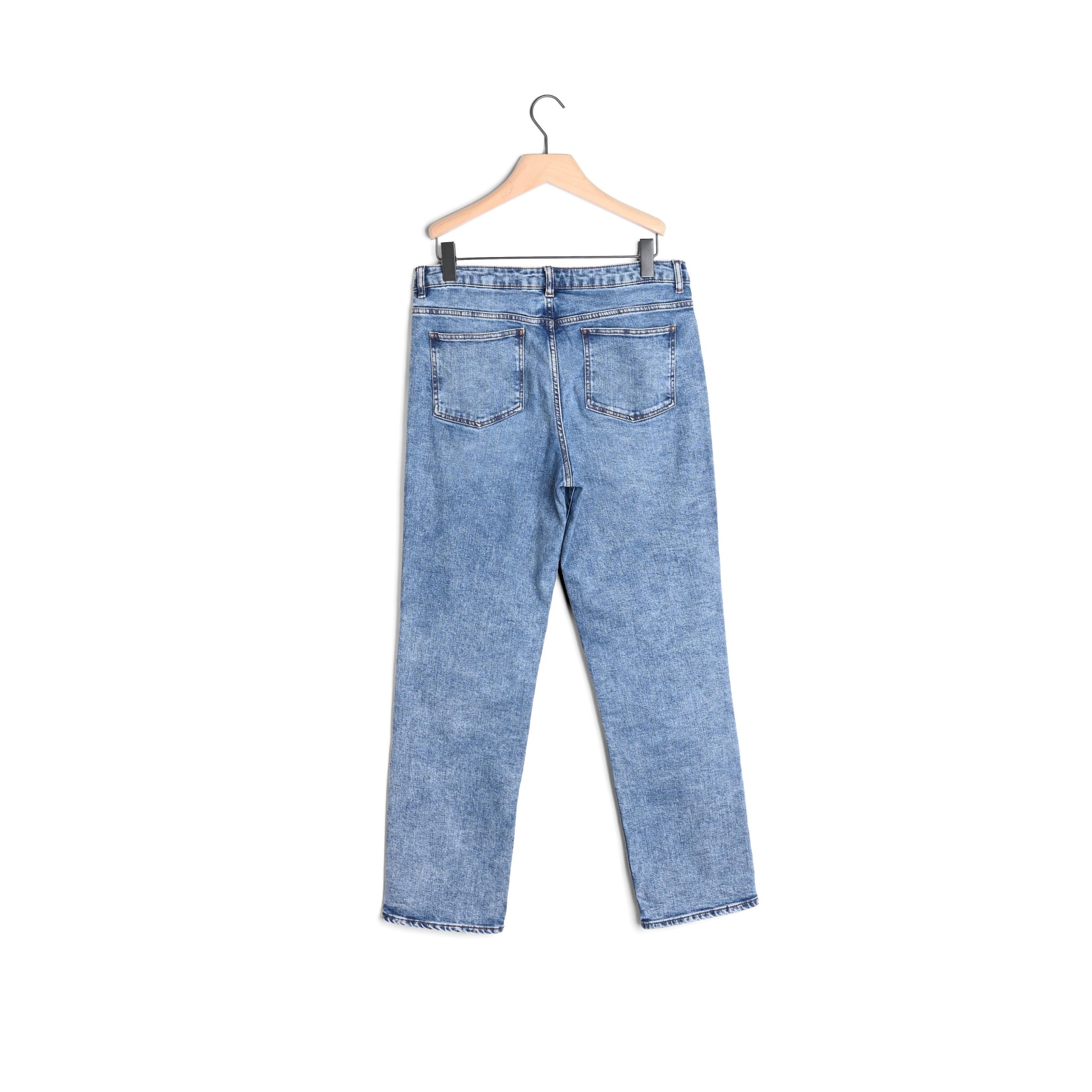 Calças de ganga azuis claras penduradas num cabide de madeira