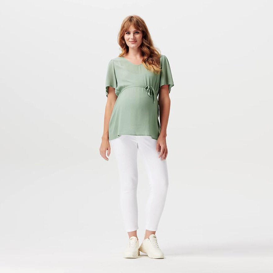 Mulher a usar camiseta verde, calças brancas e ténis brancos