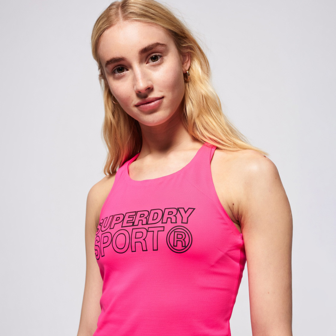 Top desportivo rosa com estampa SUPERDRY SPORT usado por mulher loira