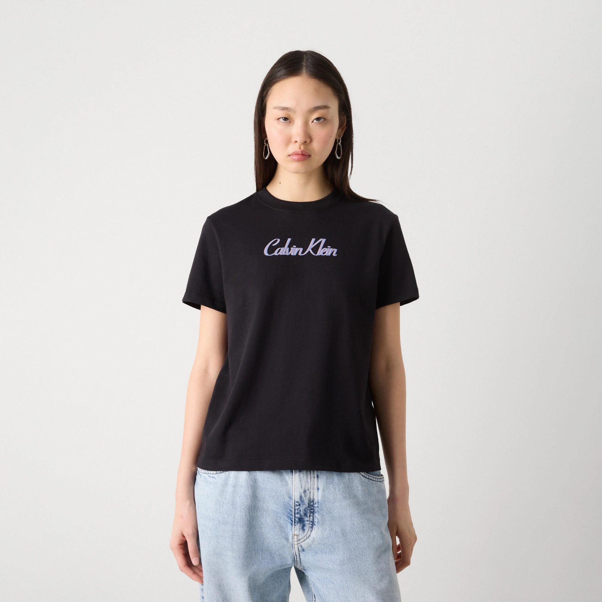 T-shirt preta Calvin Klein de algodão com logo azul claro no peito e calças de ganga claras