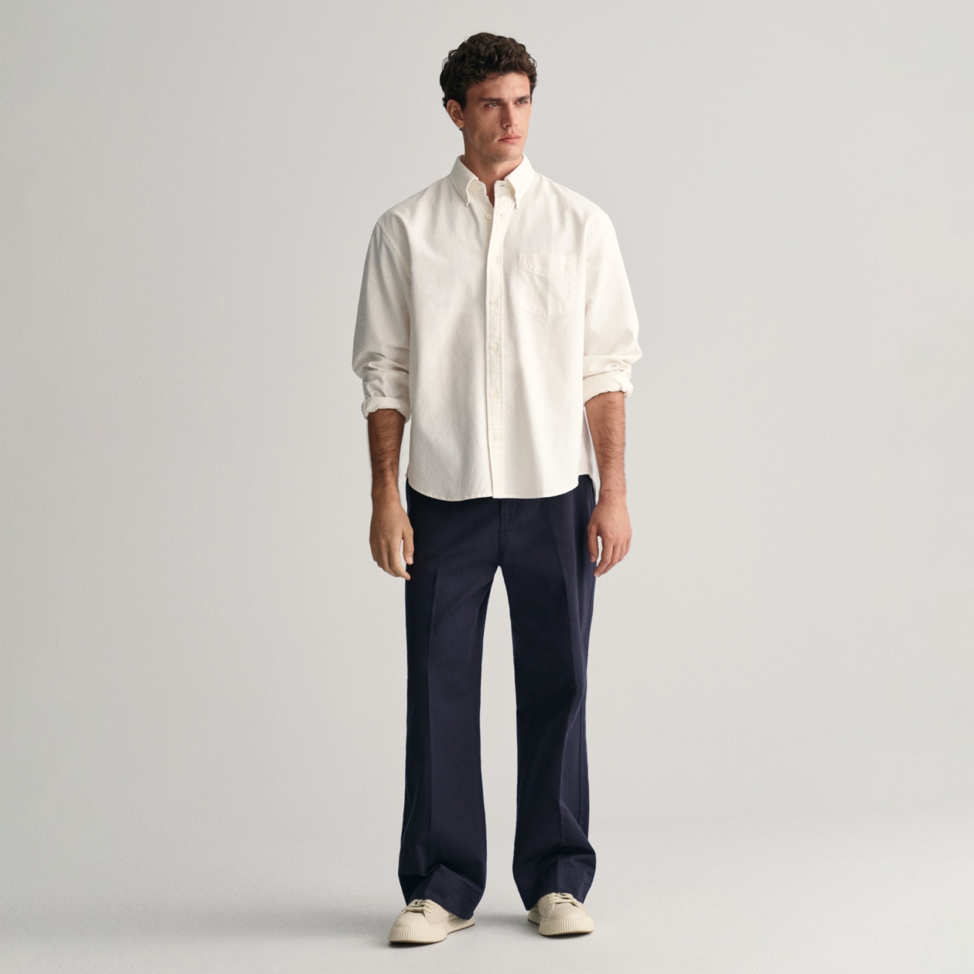 Homem com camisa branca, calças azuis escuras e sapatos brancos