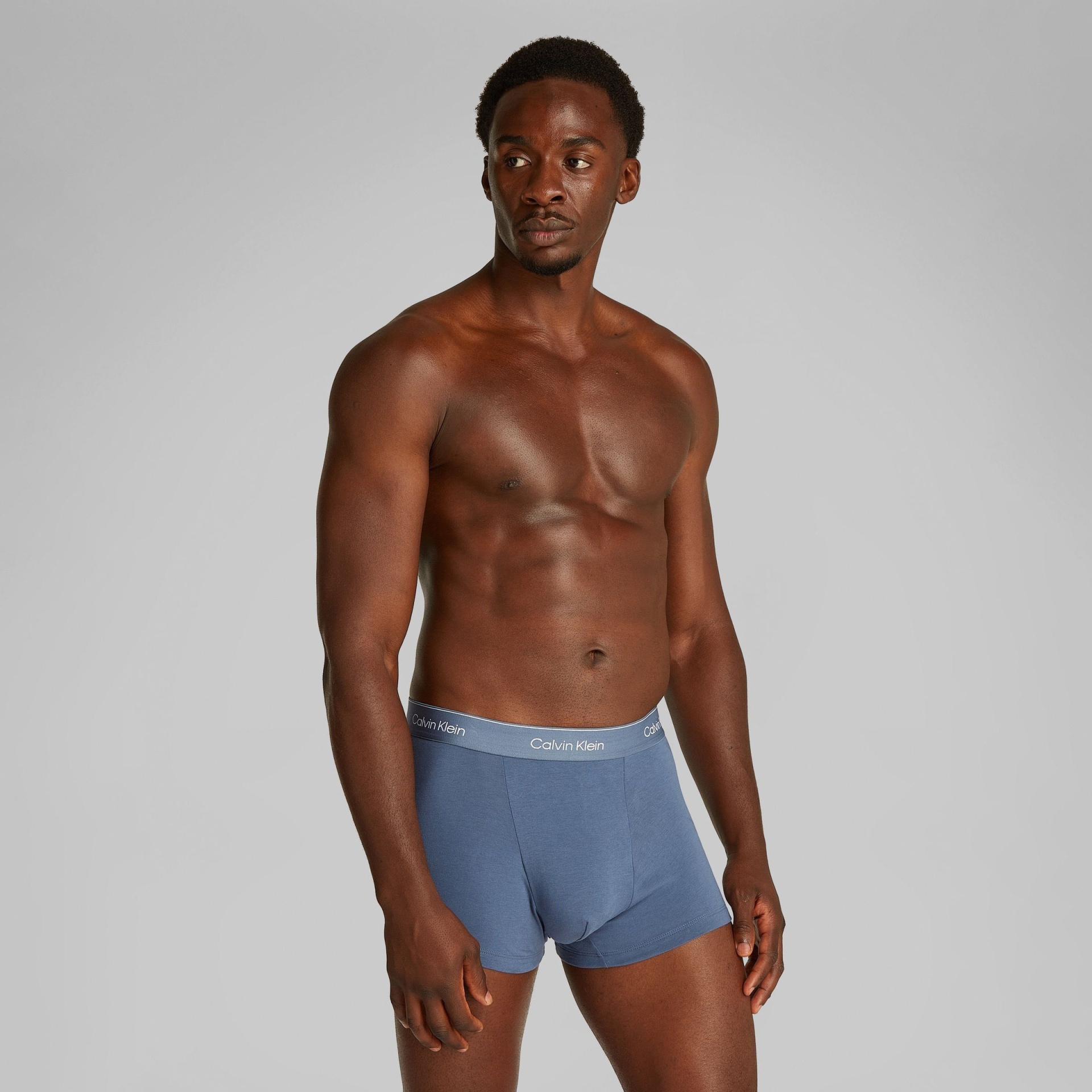 Homem a usar boxers azuis com cintura cinzenta e logo Calvin Klein
