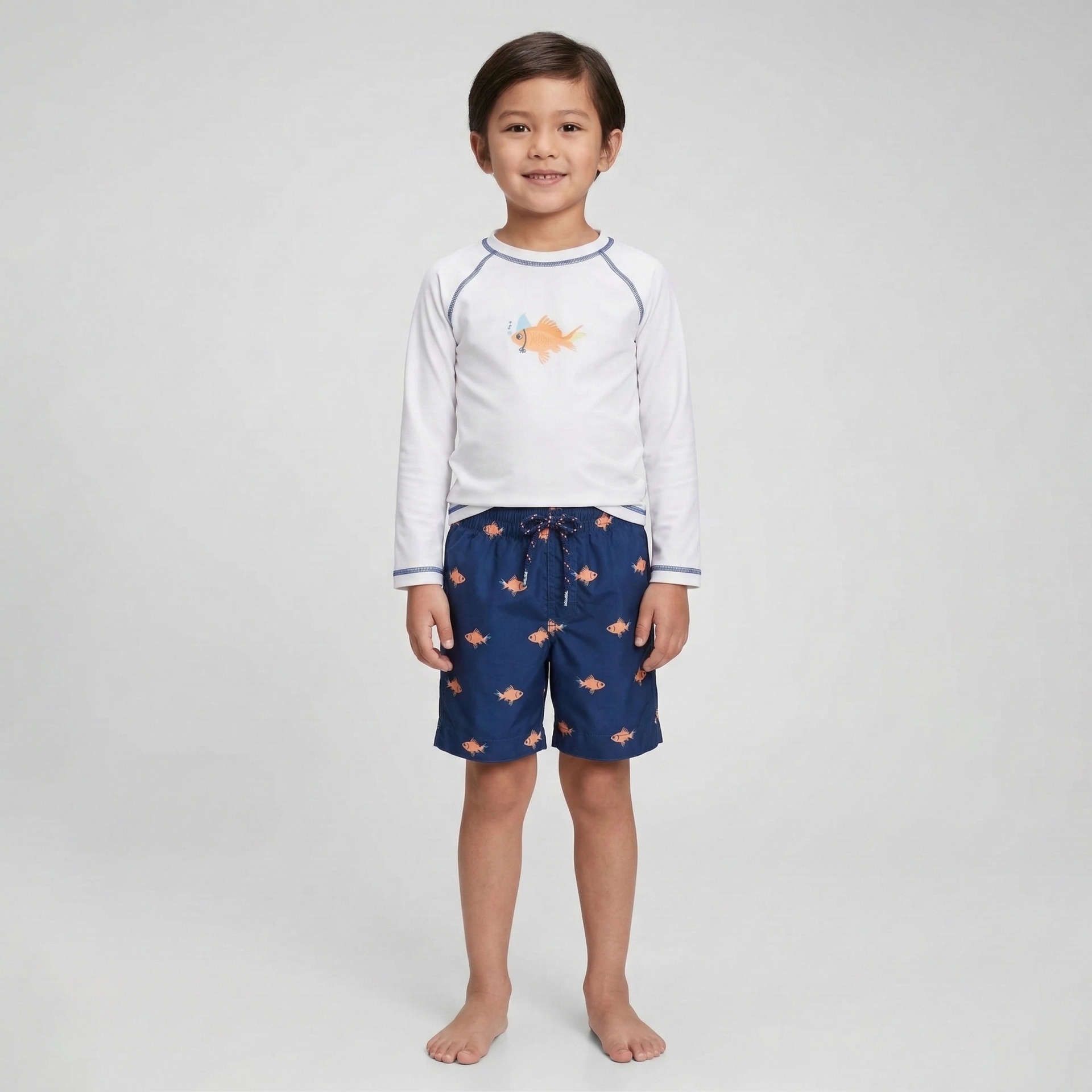 Menino com roupa de praia infantil com estampa de peixes.