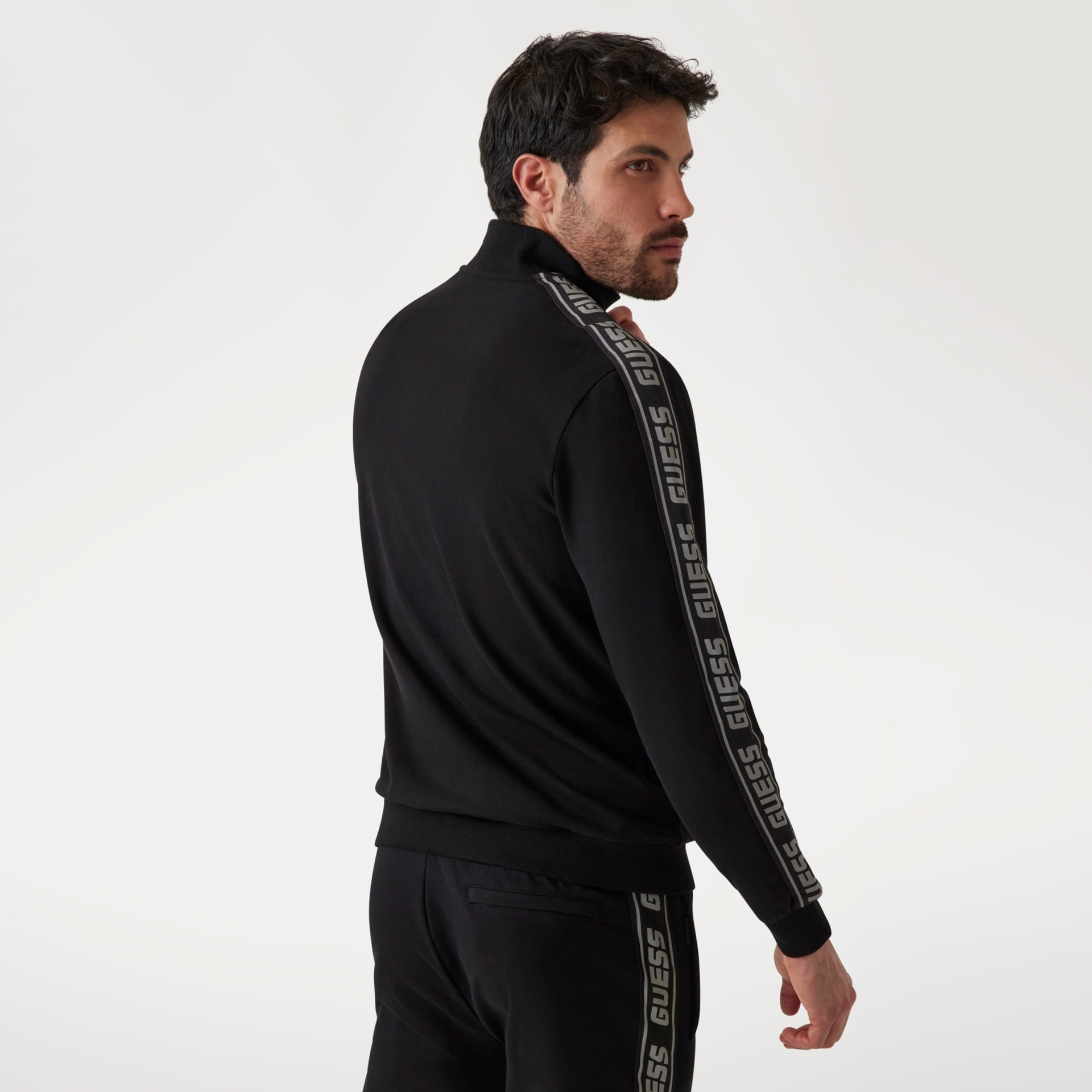 Conjunto desportivo preto de homem com faixas laterais cinza com o texto GUESS