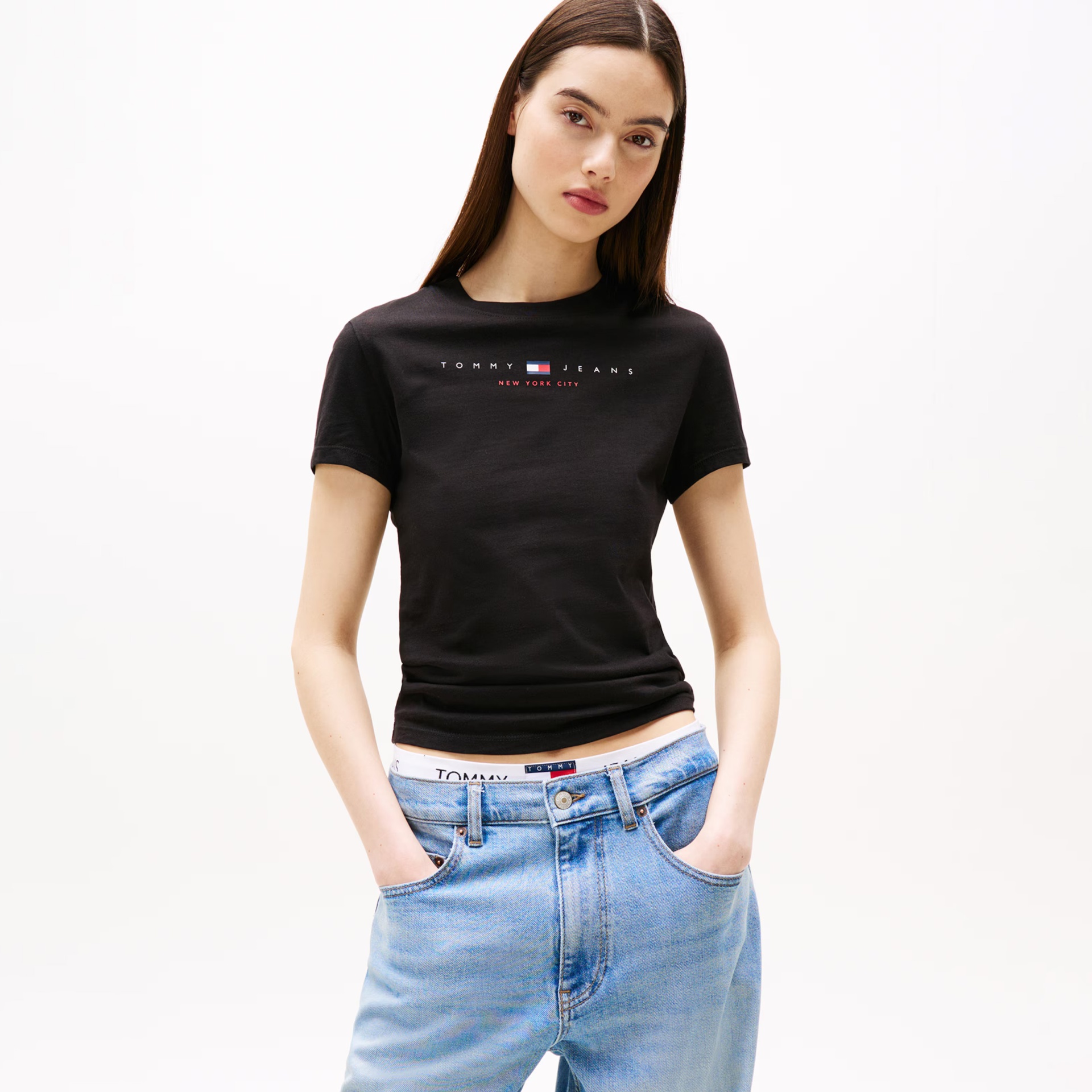 Mulher a usar t-shirt preta Tommy Jeans e calças de ganga azuis claras
