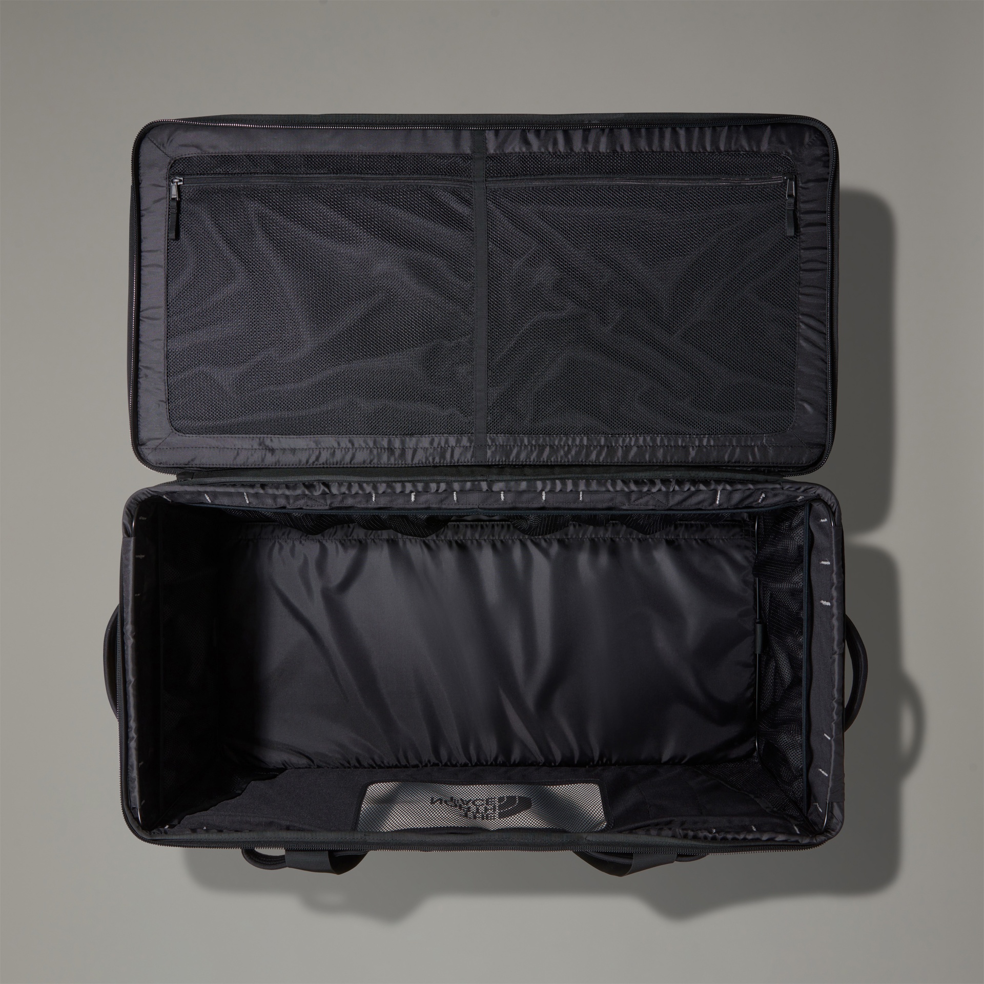 Mala de viagem preta aberta com interior espaçoso e divisória em rede.