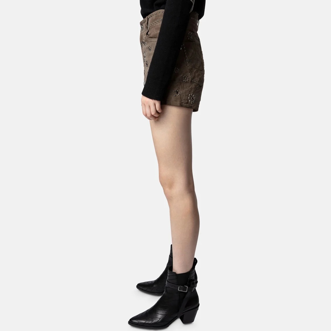 Shorts camurça castanhos com tachas florais ao lado de botas pretas