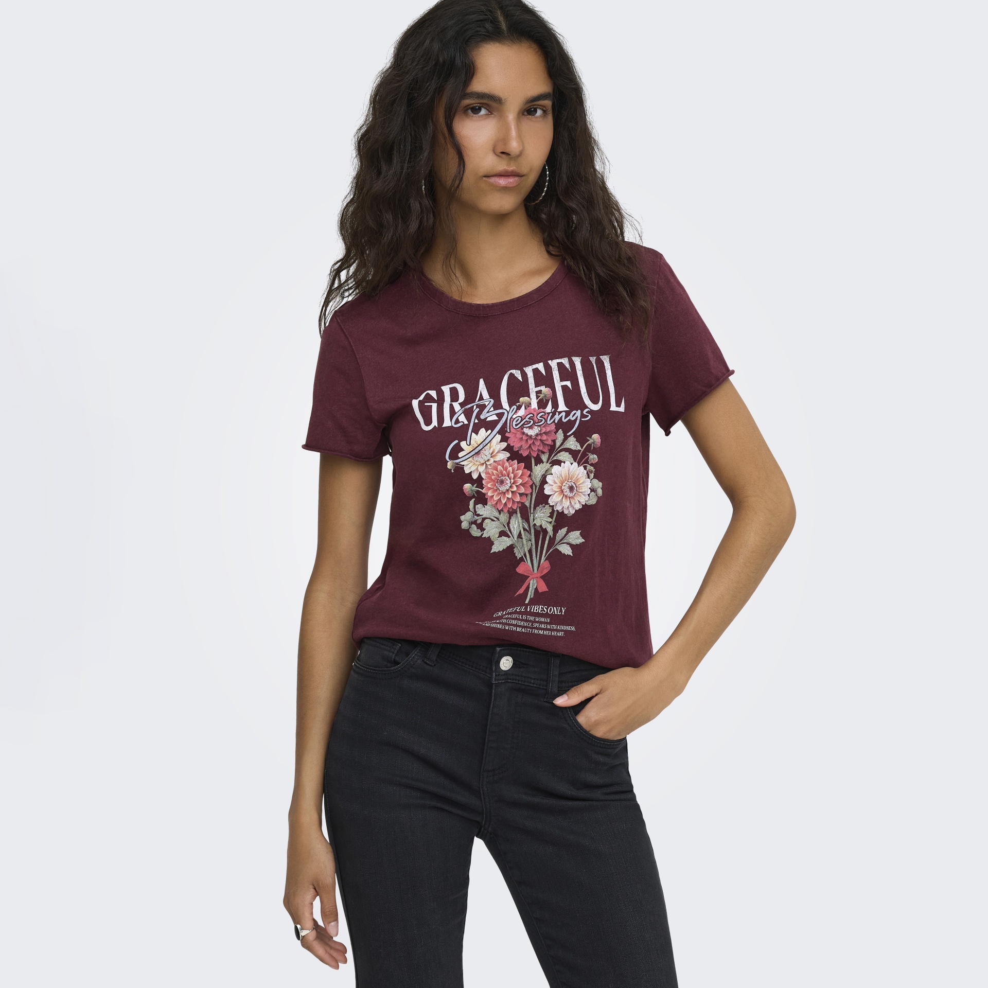T-shirt feminina bordeaux com flores e texto branco, usada com calças pretas