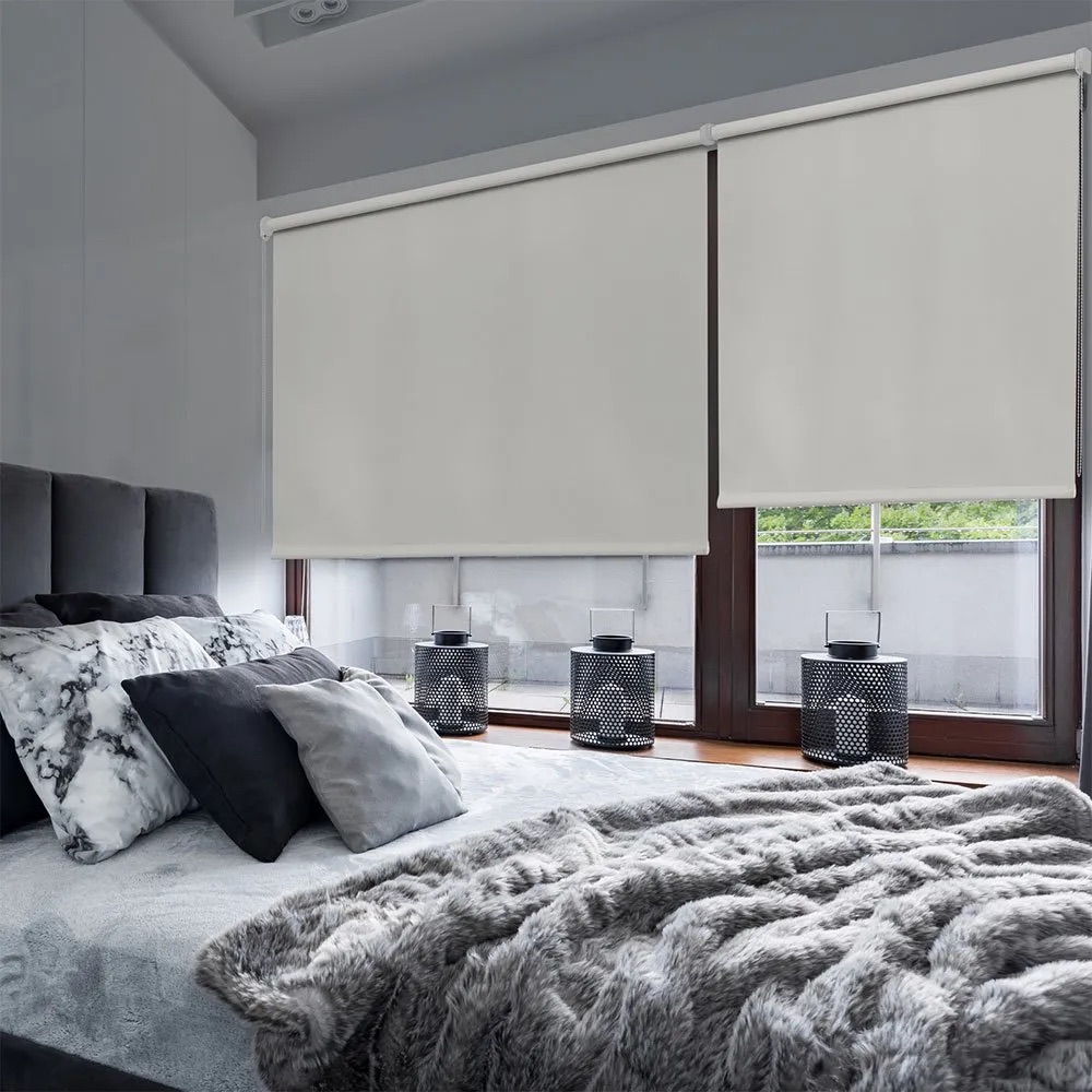 Quarto com cama, almofadas cinzentas e pretas, persianas brancas e lanternas pretas na janela