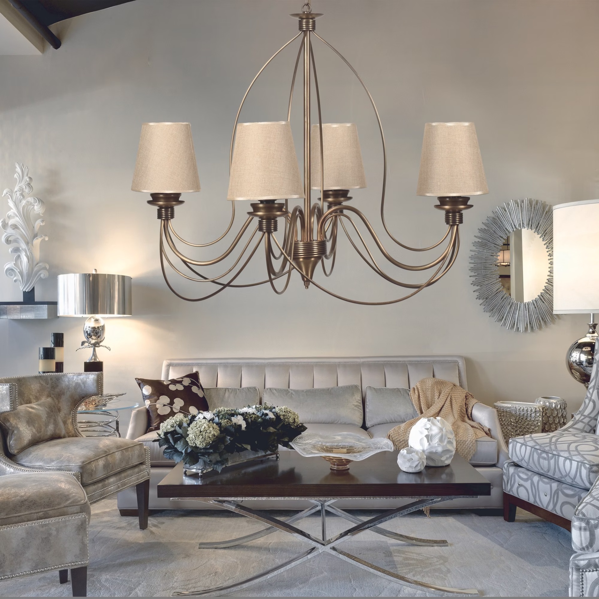 Lustre com cúpulas bege numa sala de estar moderna com sofá cinza e mesa de centro em madeira.