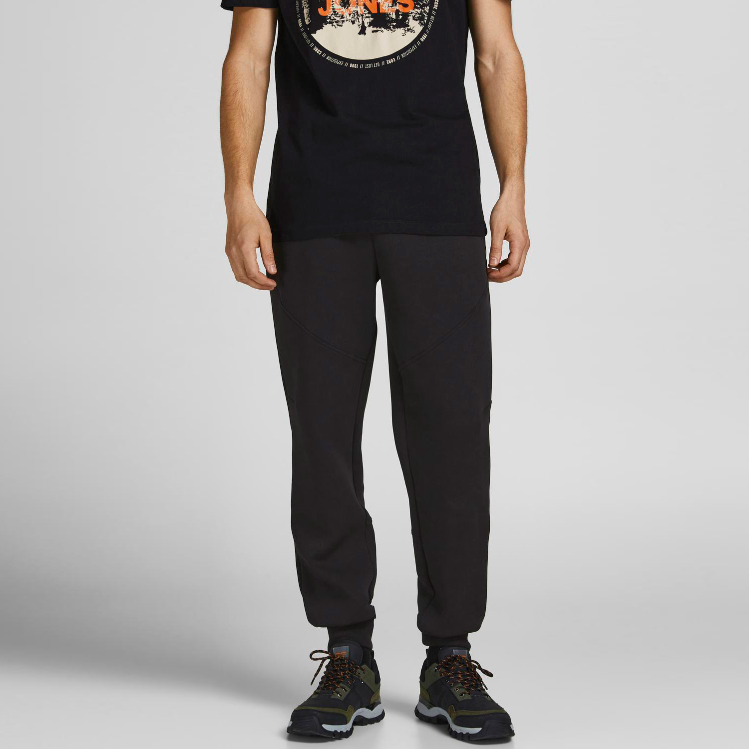 Calças de corrida pretas com bainha ajustada usadas com ténis e t-shirt preta