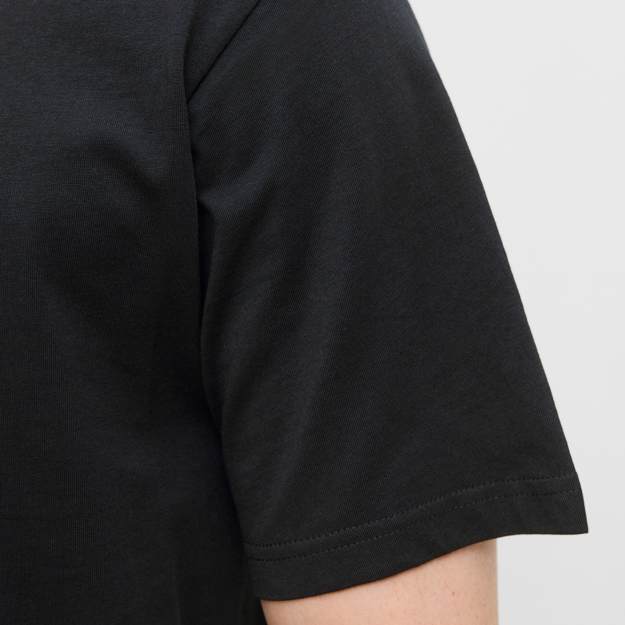 Manga curta de t-shirt preta de tecido liso com costura visível