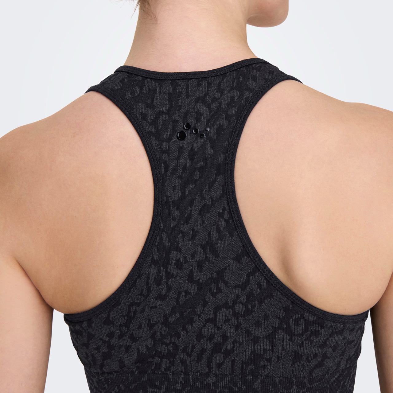 Parte traseira de top desportivo preto com padrão leopardo e símbolo preto