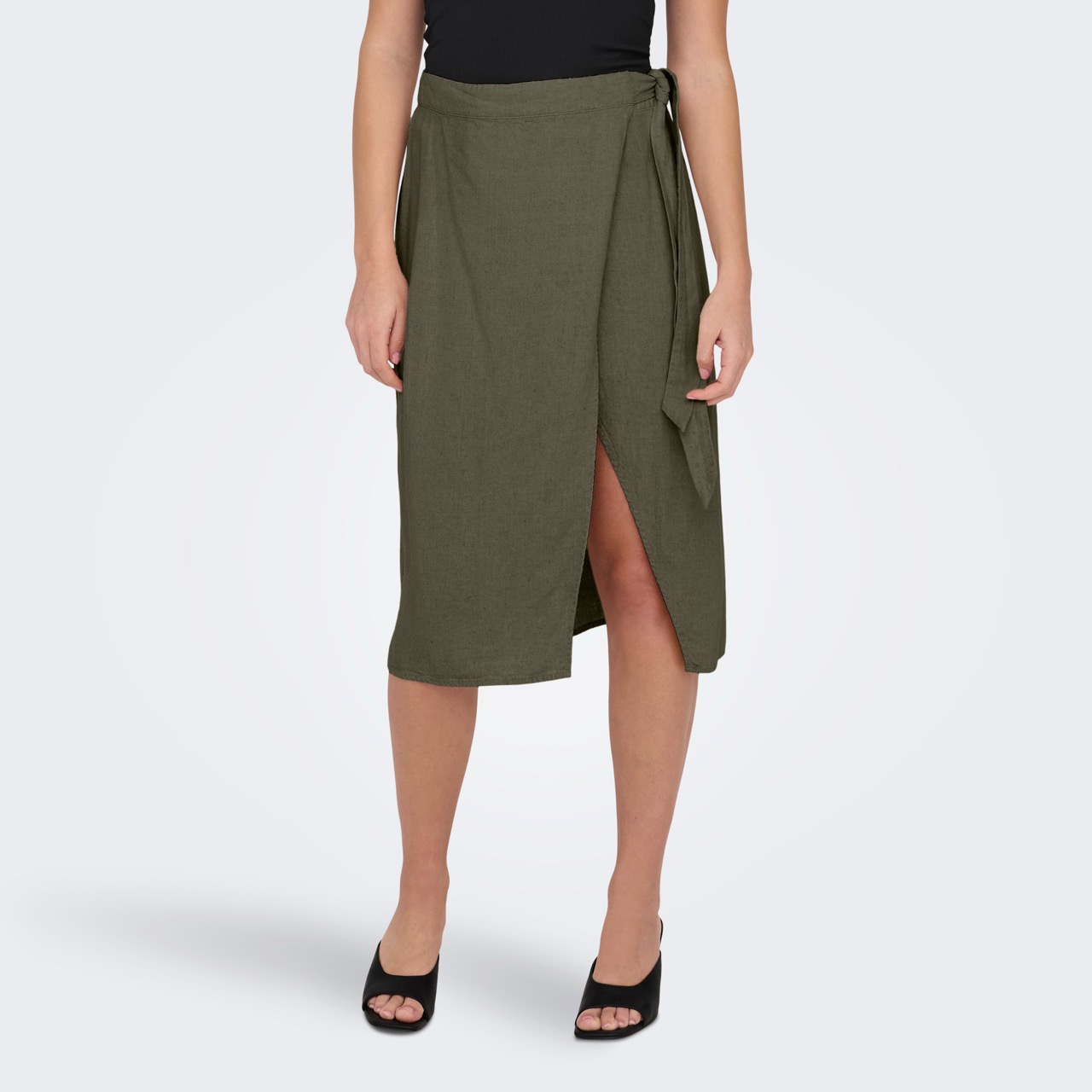 Saia midi verde oliva com transpasse e cinto, usada com top preto e sapatos pretos