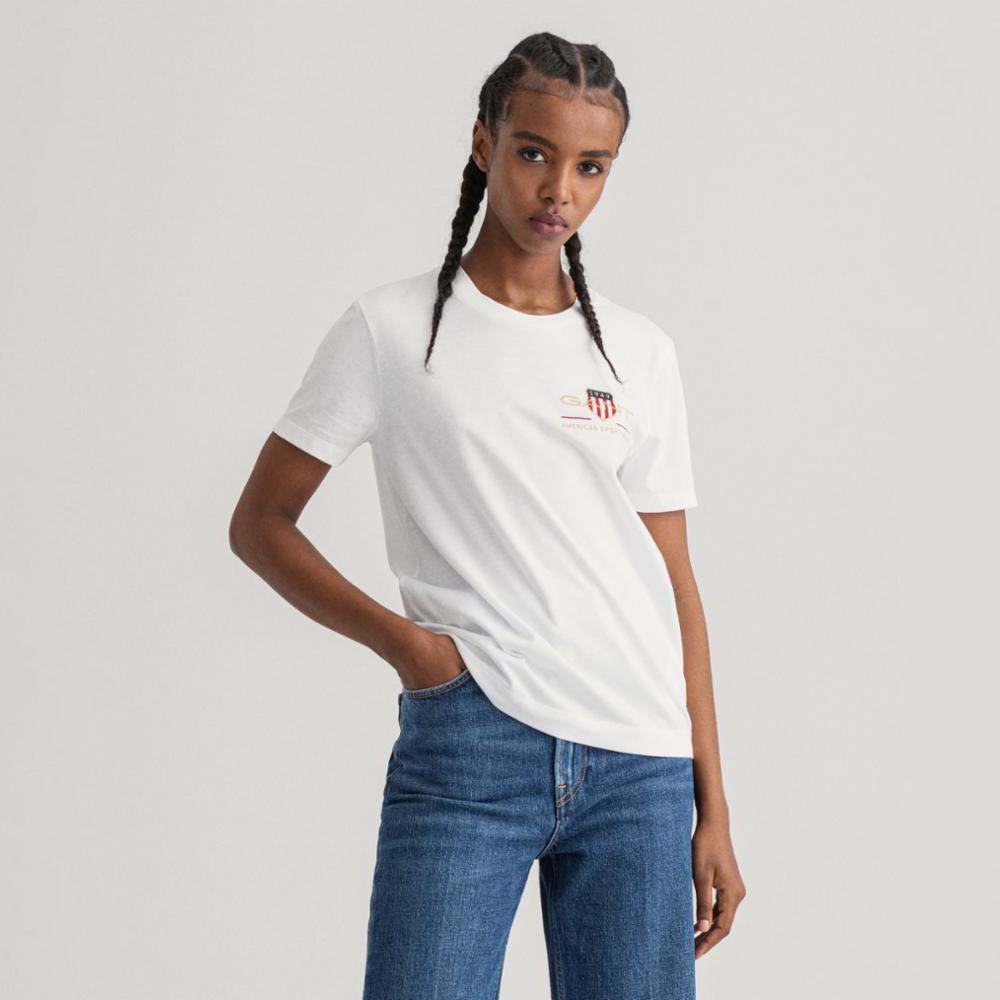 Mulher a usar t-shirt branca com logotipo e jeans azuis em fundo neutro