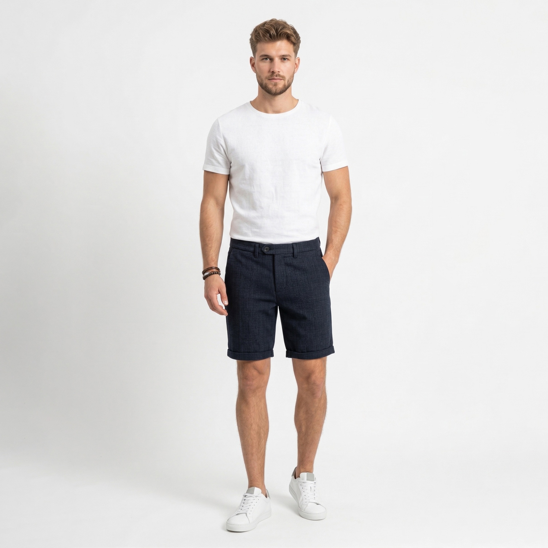 Homem com t-shirt branca, calções azuis escuros e ténis brancos