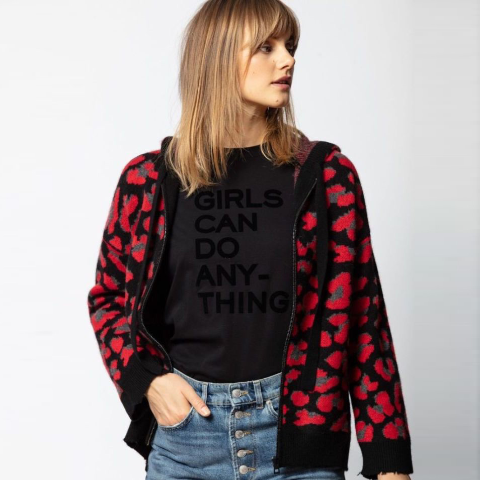 Mulher a usar camisola preta com texto e casaco de malha com padrão floral vermelho e cinza