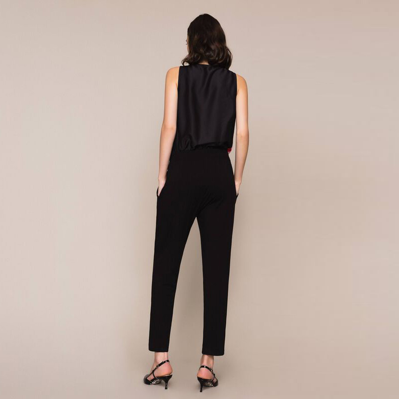 Mulher vista de costas com macacão preto sem mangas e calças compridas.