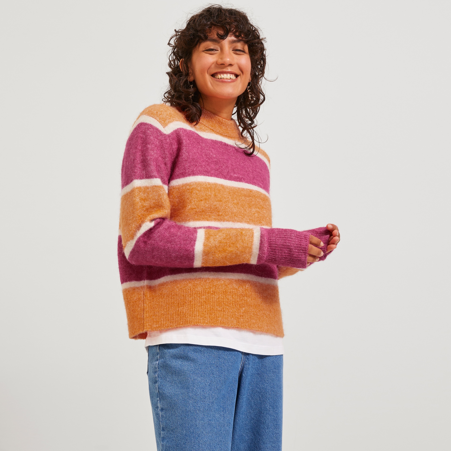 Camisola de malha às riscas rosa, laranja e branco com gola redonda e calças de ganga azuis