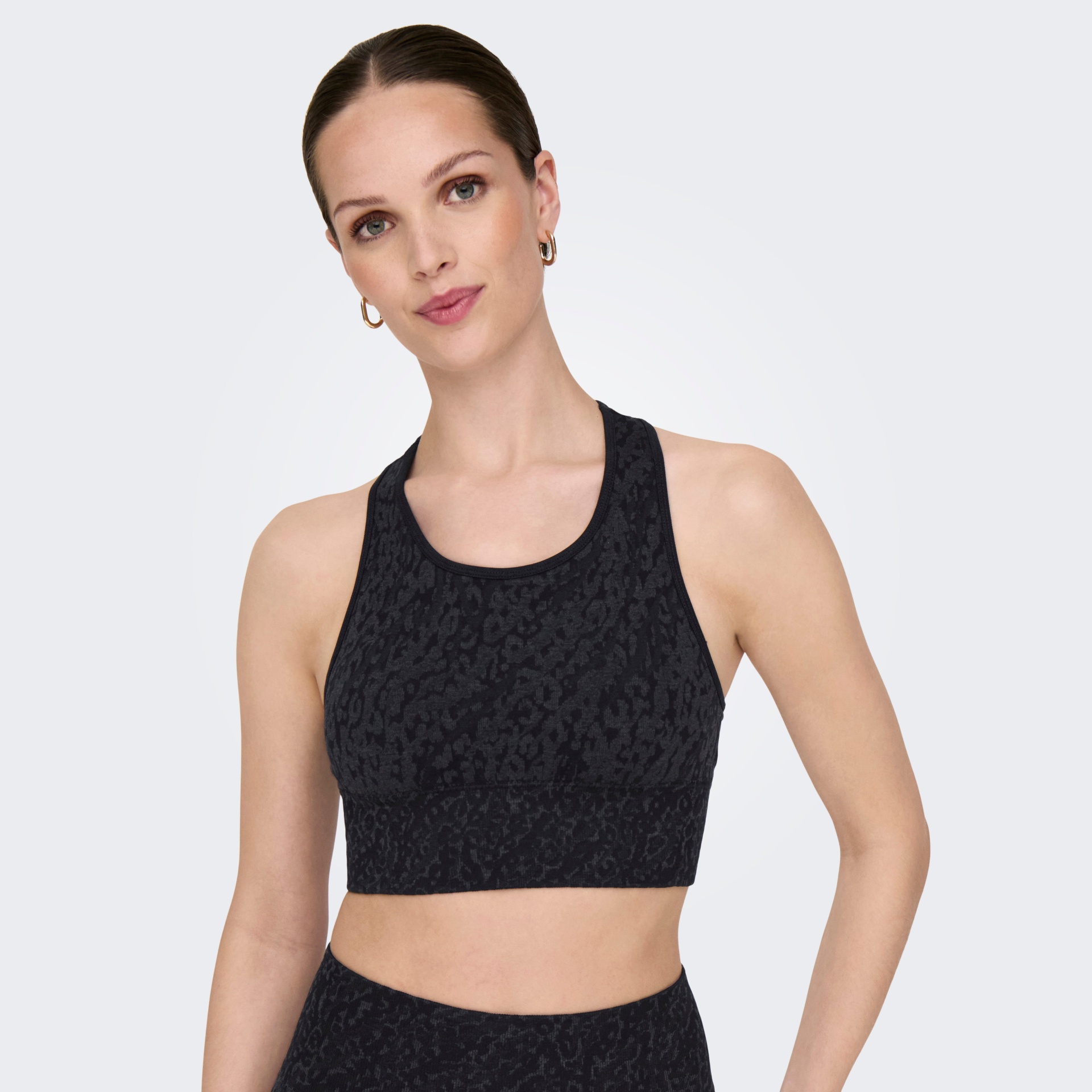 Top desportivo preto com padrão animal texturizado mostrado por mulher