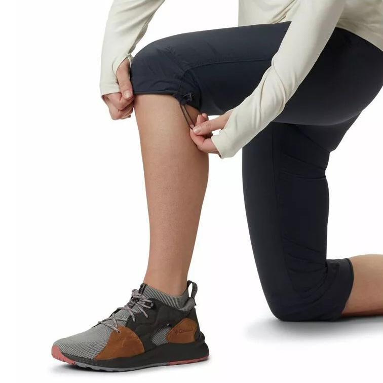 Calças desportivas pretas até ao joelho com sapatos cinza e castanhos