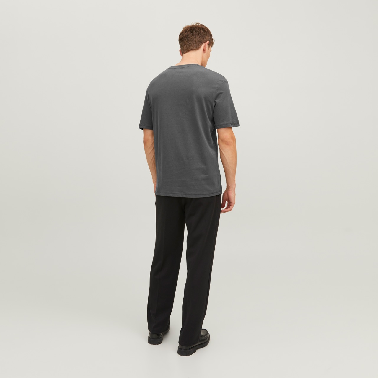 Homem de costas com t-shirt cinzenta e calças pretas