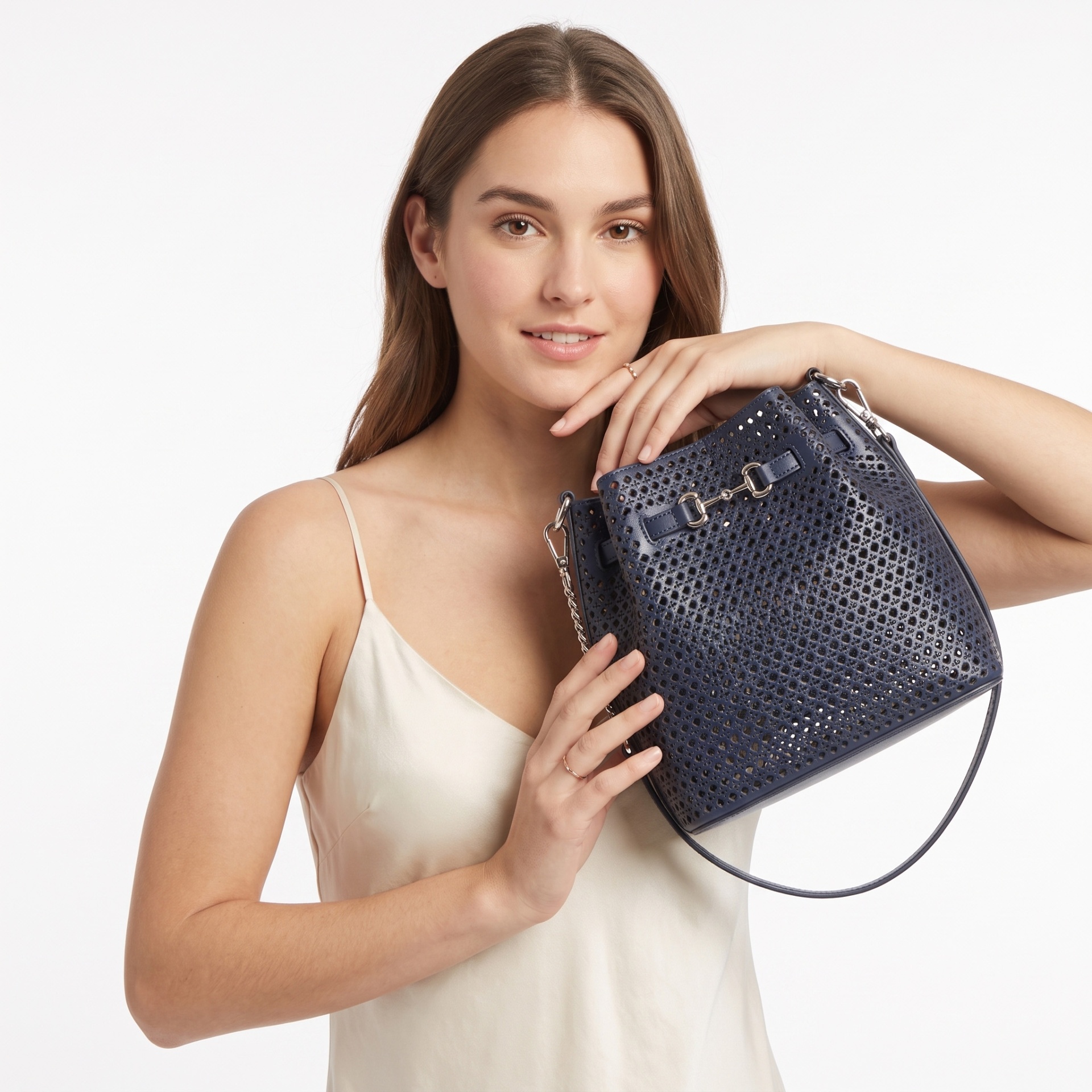 Mulher com top branco segurando mala azul-marinho com padrão perfurado e alça