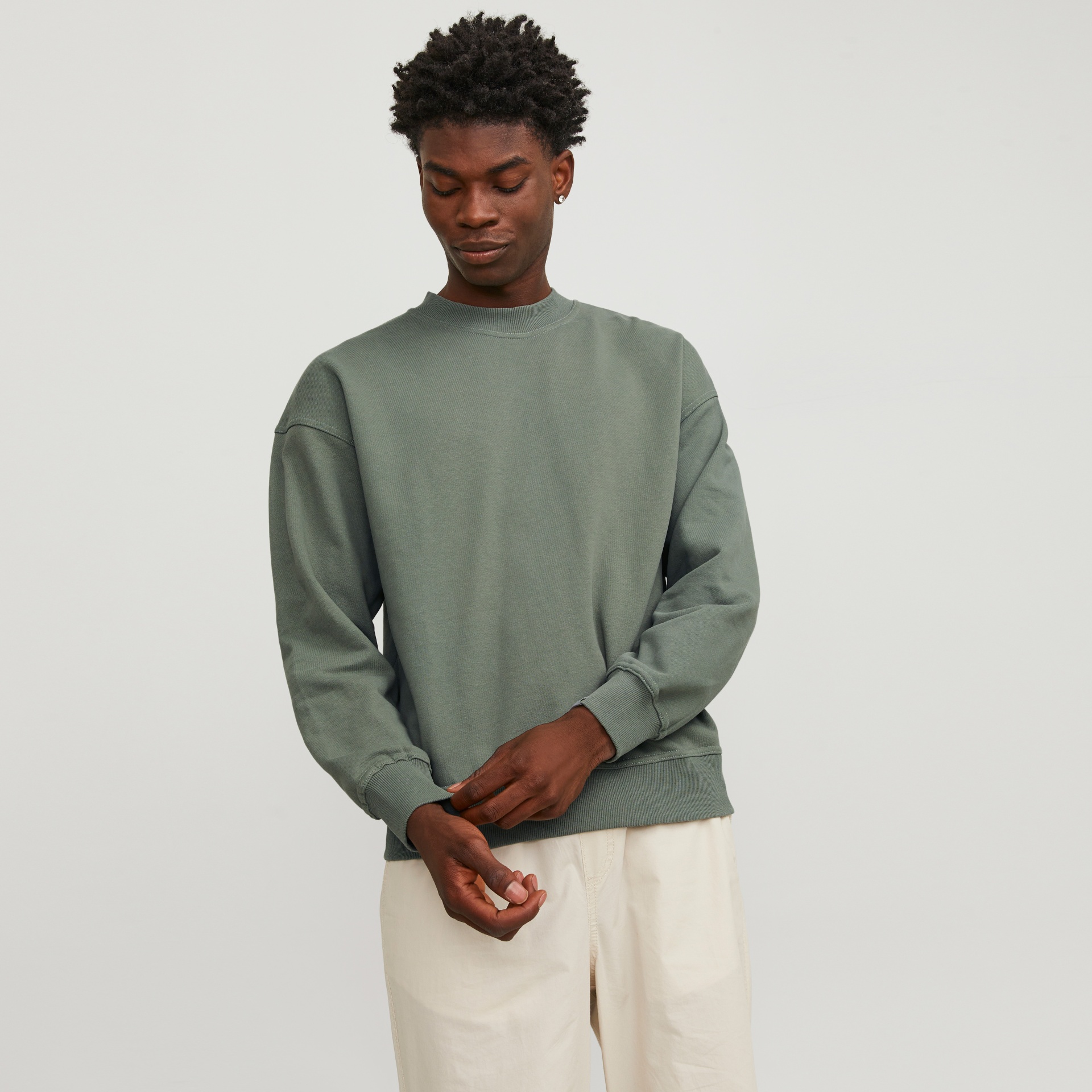 Homem com sweatshirt verde musgo e calças bege
