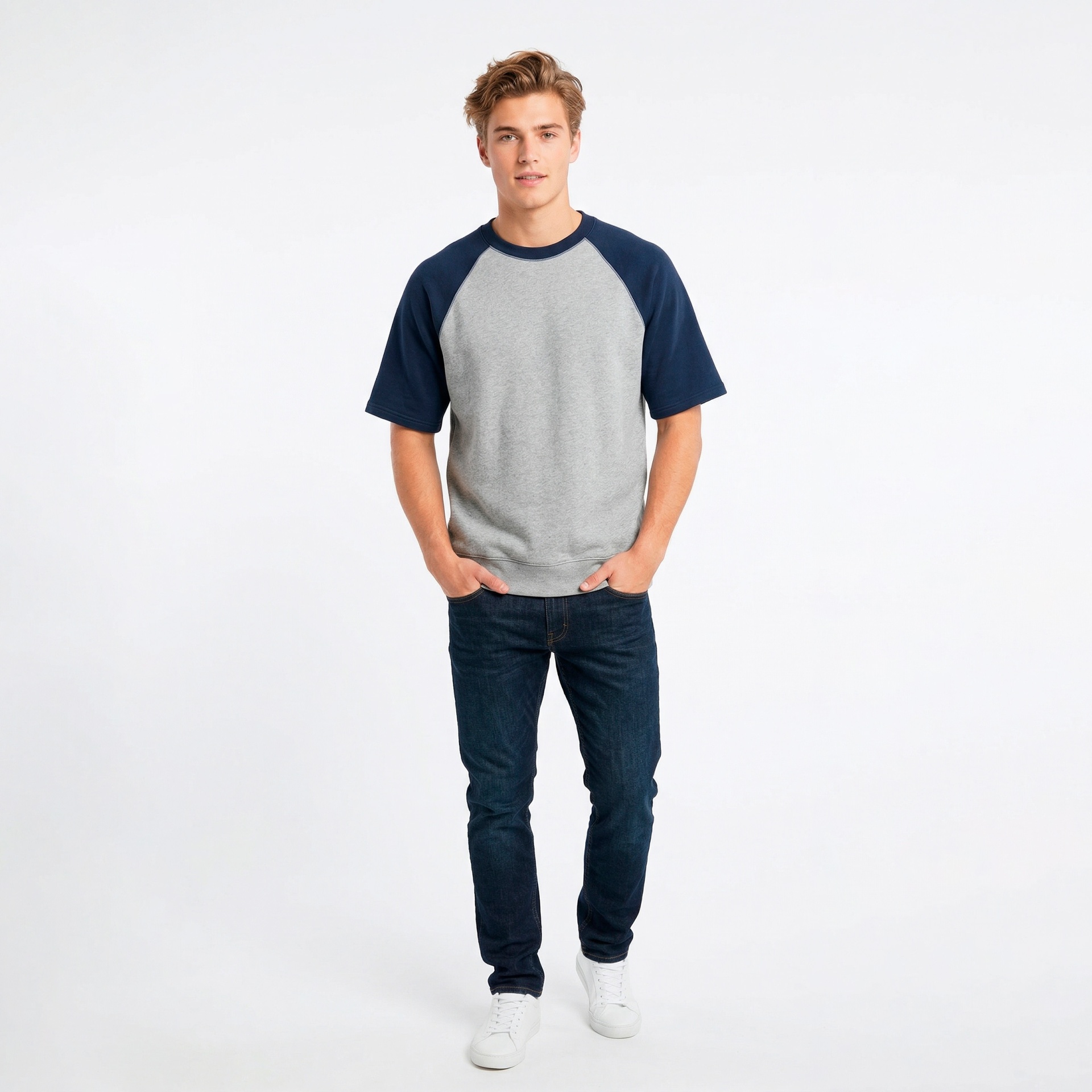 Homem com T-shirt cinzenta e azul, jeans azul e sapatilhas brancas