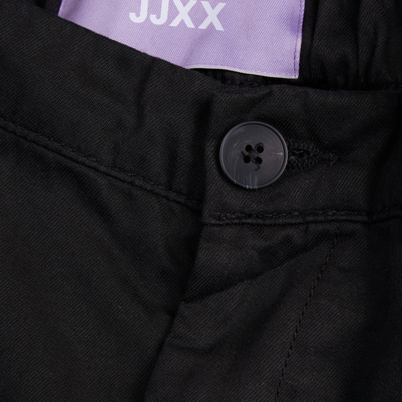 Peça de roupa preta com botão e etiqueta roxa JJXX
