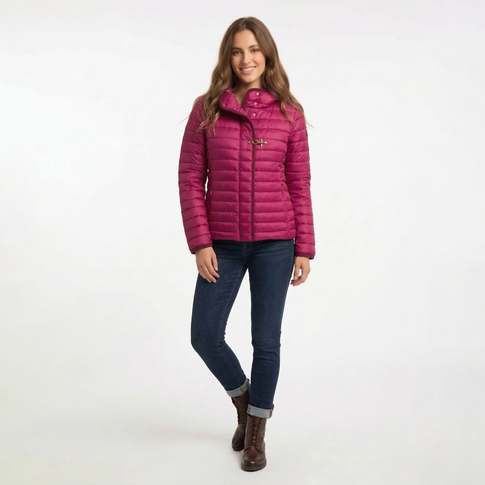 Mulher com casaco rosa acolchoado, jeans e botas, fundo branco