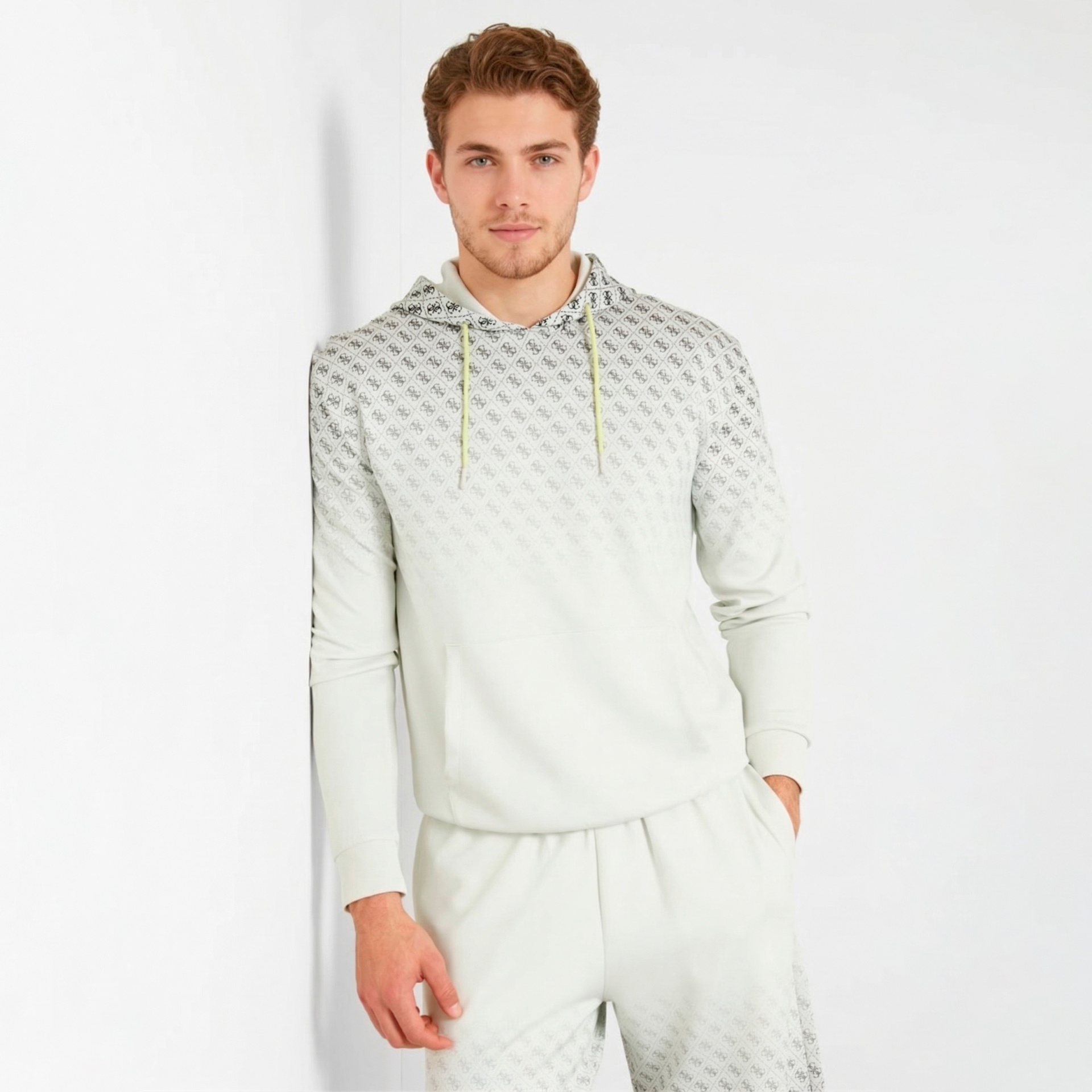 Homem a usar sweatshirt com capuz e calças com padrão geométrico cinza e preto em fundo claro