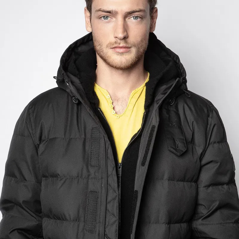 Homem com casaco preto grosso e capuz e camiseta amarela