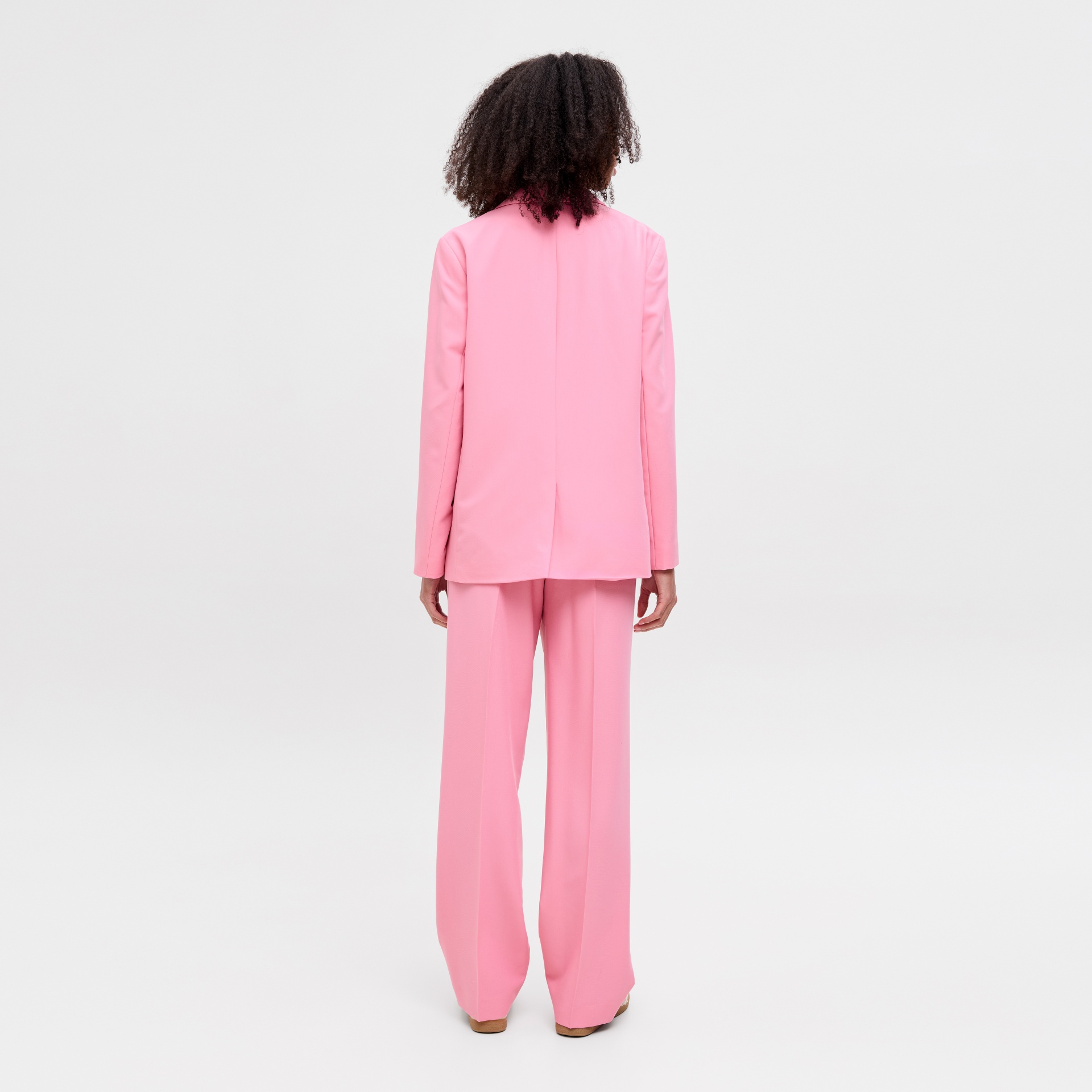 Mulher de costas a usar blazer e calças rosa largas