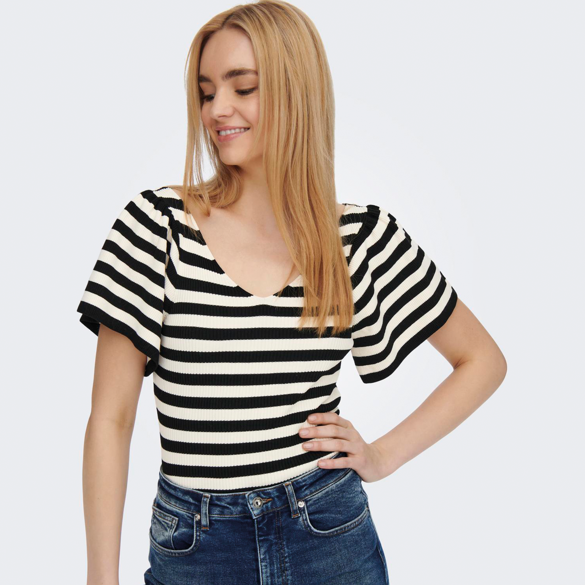 Top feminino de malha riscas pretas e brancas com mangas bufantes e calças de ganga azul escuro