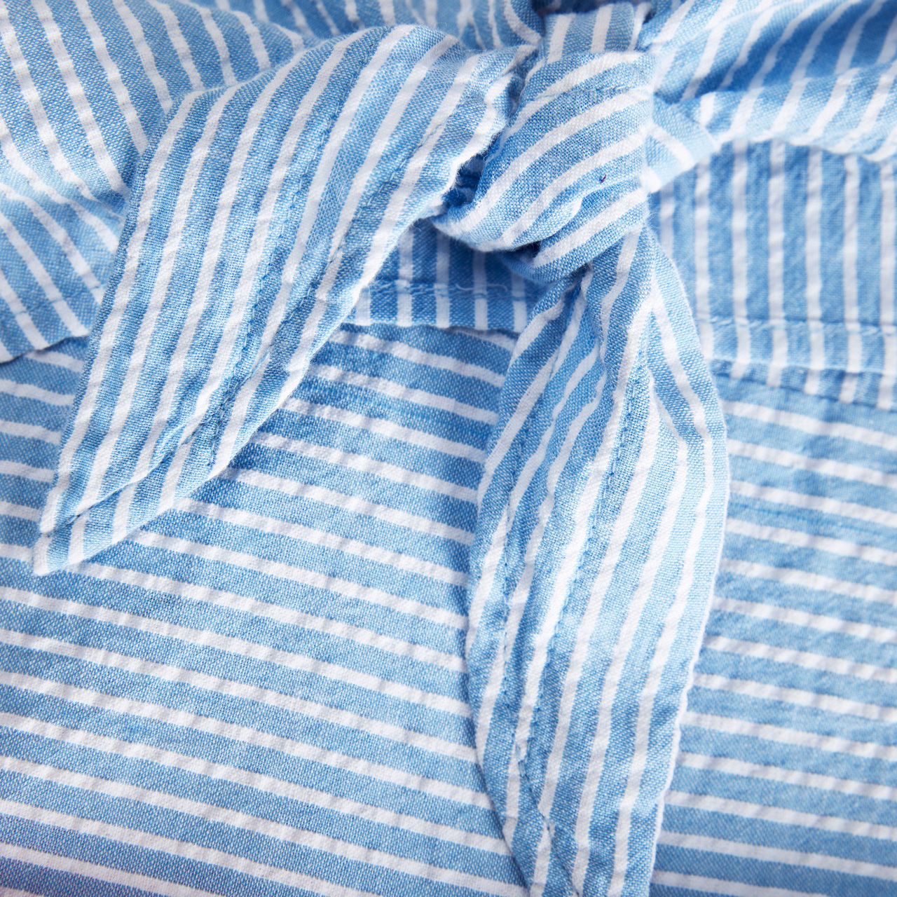 Tecido azul claro com riscas brancas e dobras