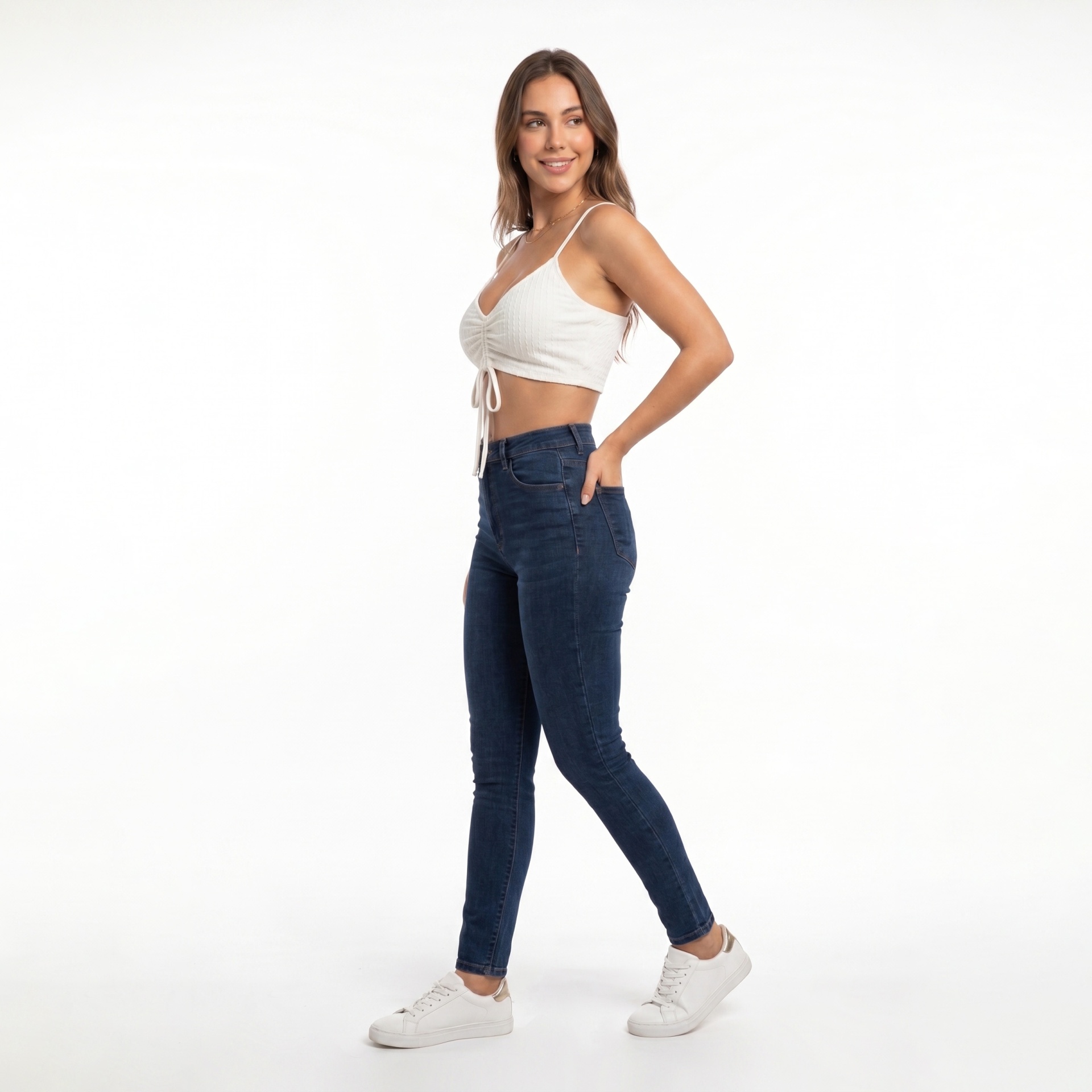 Mulher com top cropped branco, jeans azul escuro e ténis brancos