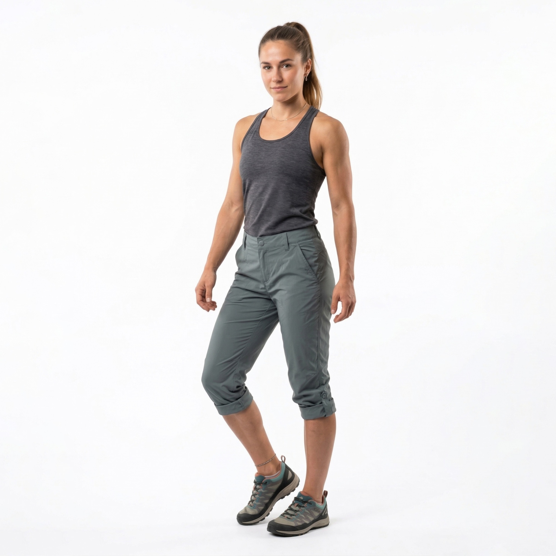 Mulher com camisola cinzenta e calças capri verdes e sapatos de trekking