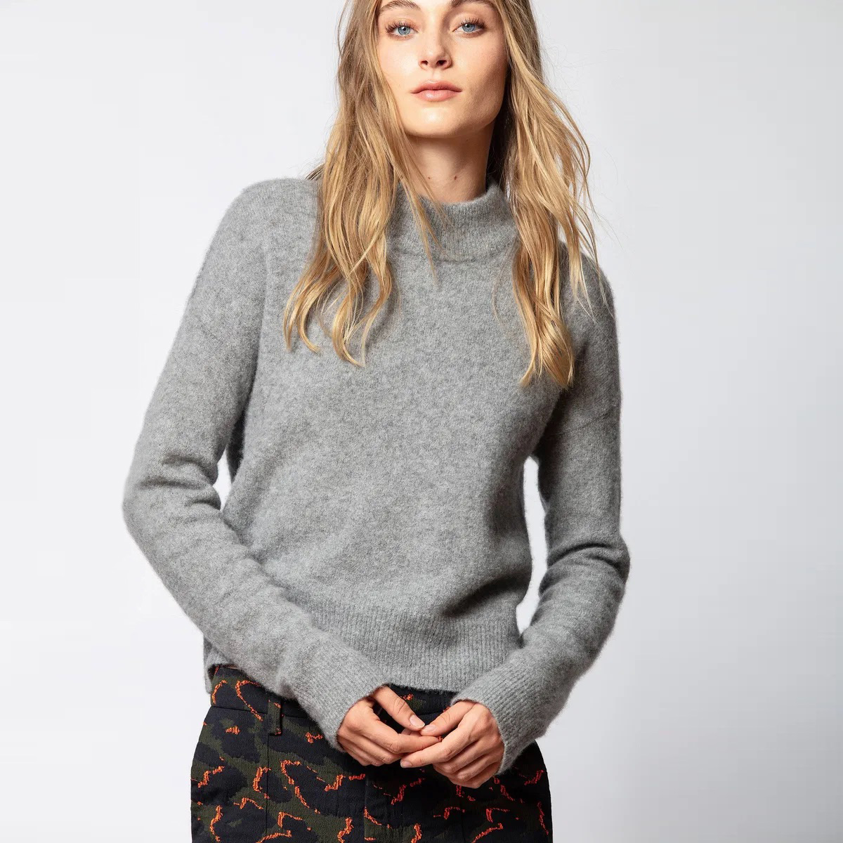 Camisola cinzenta de malha com gola subida e calças pretas com padrão abstrato