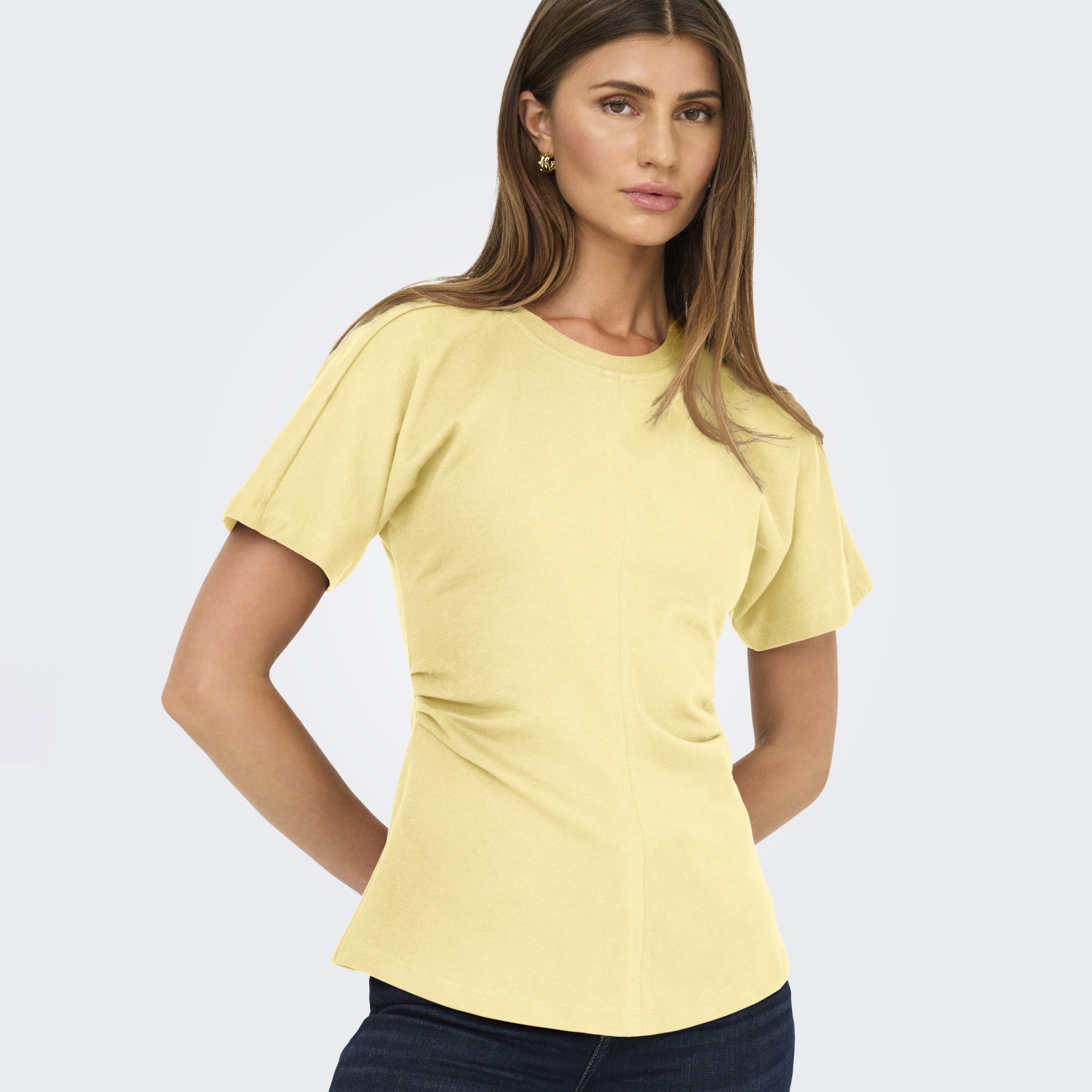 Mulher com t-shirt amarela de manga curta e calças escuras